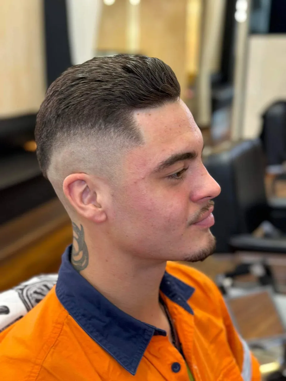 Client in the chair with a high skin fade, short textured top and a clean line-up at the temple